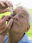 Man putting eye drops in his eye