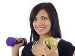 Girl holding an apple in one hand and dumbbell in the other 