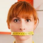 Woman with a measuring tape on her lips