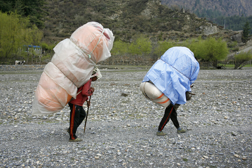 Men carrying heavy loads on back