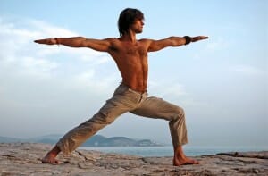 Man doing yoga outdoors. Virabhadrasana. Side view.