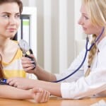 woman doctor measuring blood pressure of patient