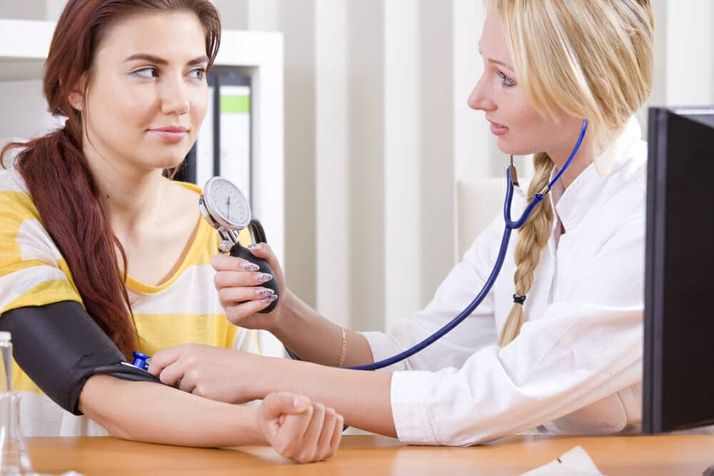 woman doctor measuring blood pressure of patient