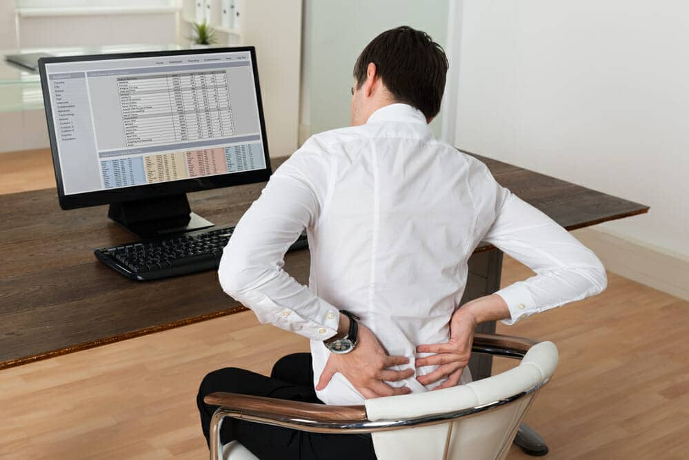 Young Businessman Sitting On Chair And Suffering From Backache At Desk