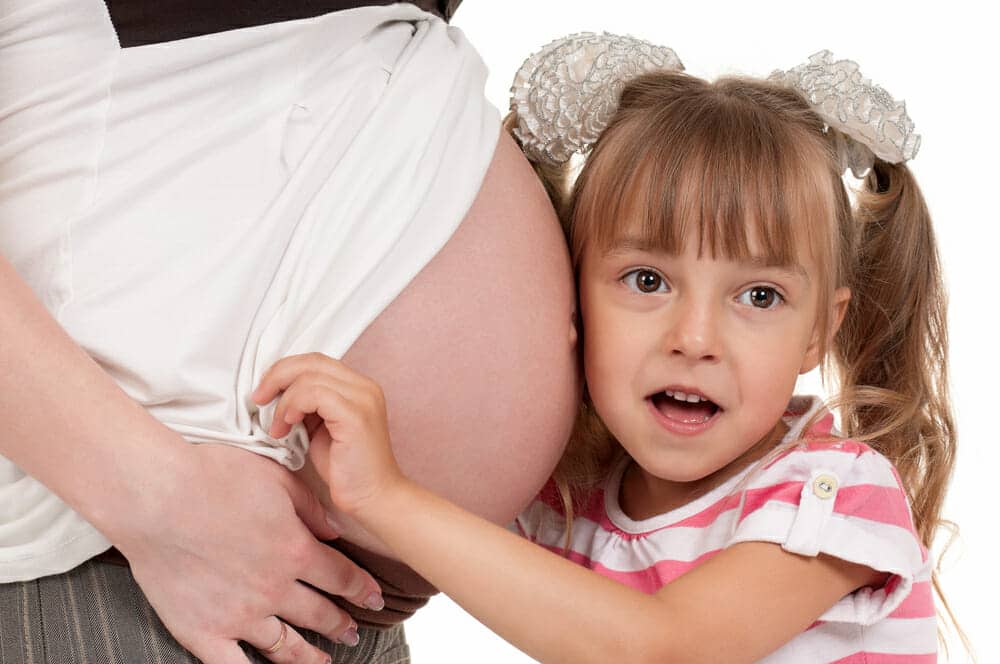Pregnant woman with her daughter - isolated over a white background. Third trimester.