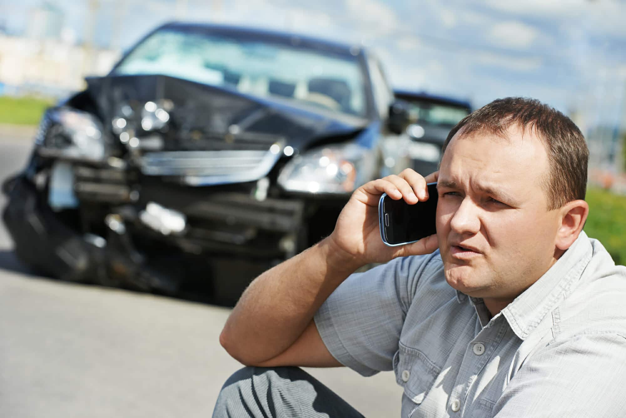 Adult upset driver man discussing on mobile phone in front of automobile crash car collision accident in city road