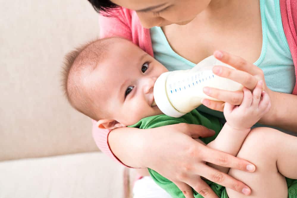Copy-spaced image of a mother feeding her little baby boy from the milkbottle on the foreground