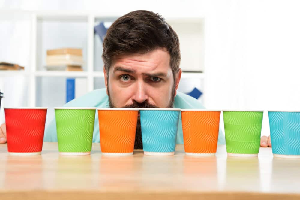 Difficult choice. decision-making. serious and sad man with colorful coffee cups. Many cups of coffee. hard choice to make. i need more coffee. low energy. Taking decisions. mature hipster man.