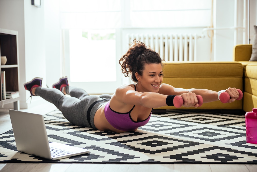 Young woman exercising at home in a living room.