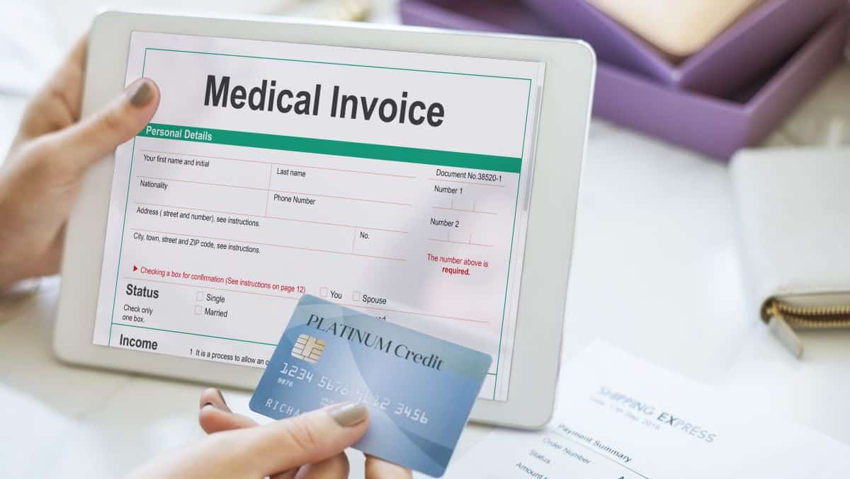 Person holding a medical invoice and credit card, representing healthcare billing fraud